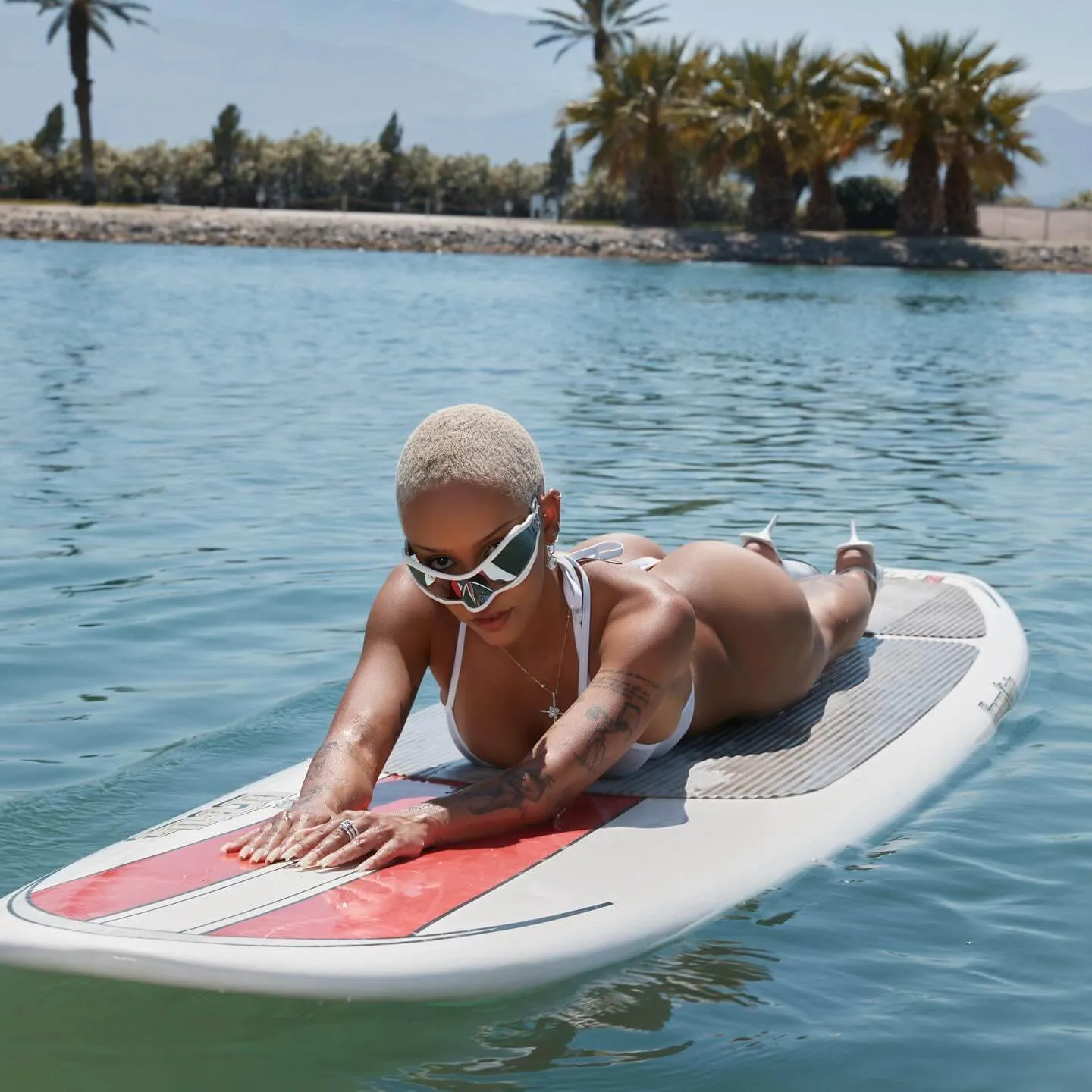 doja cat bikini in transparant white swimsuit lieing flat on the surf boat image